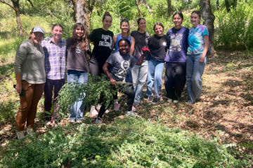 Colfax High School Environmental Club poses with a huge pile of invasive broom plants that they've removed
